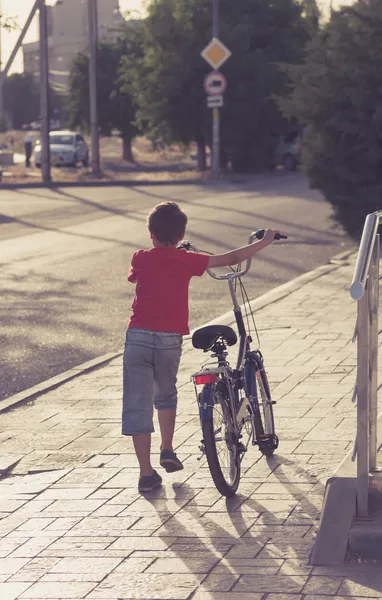 Portret van een schattige jongen lopen in de buurt van zijn fiets — Stockfoto