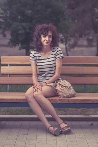 Güzel bir kız bir bankta oturan — Stok fotoğraf