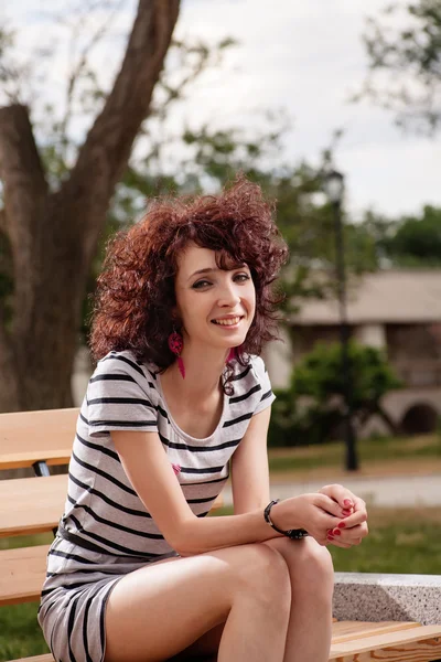 Une belle fille est assise sur un banc de parc — Photo