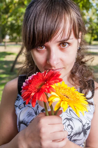 Brunett med blommor i händerna — Stockfoto