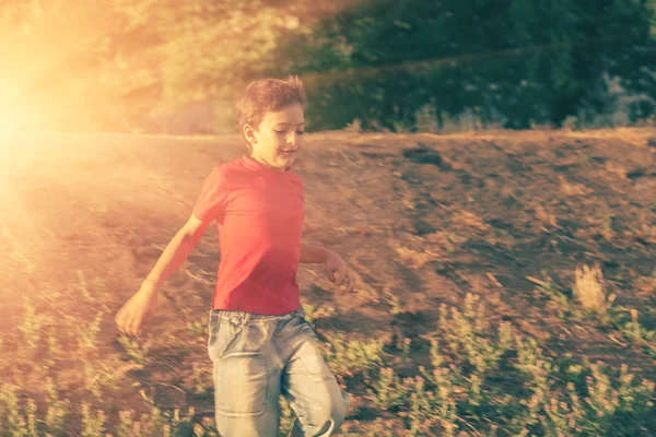Cute boy running down the slope backlit — Stock Photo, Image