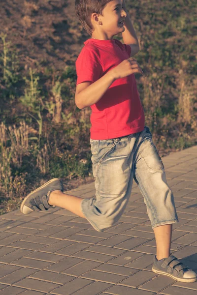 Pojke slitna röd t-shirt och jeans shorts kör — Stockfoto