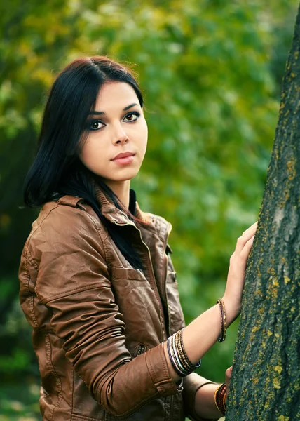 Niedliches ruhiges Mädchen, das dich ansieht, wie du neben Baum stehst — Stockfoto