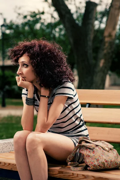 Una bella ragazza è seduta su una panchina del parco — Foto Stock