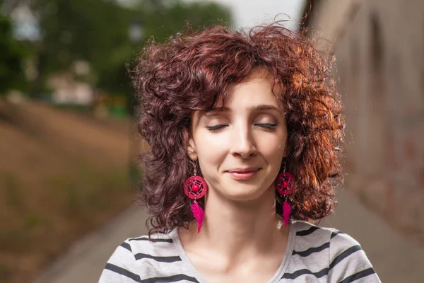 Curly haired women outdoors with her eyes closed. Pretty smile — Stock Photo, Image