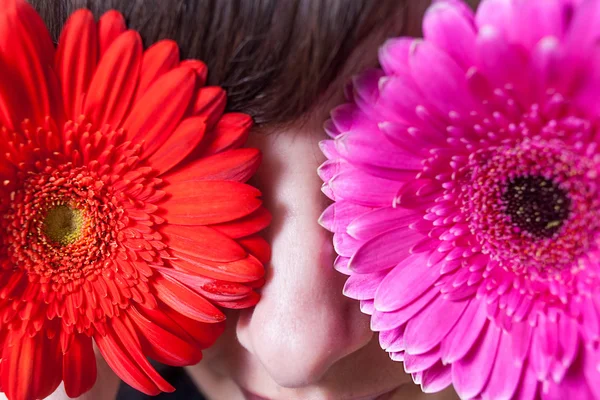 Aranyos lány elrejti a szemét gerbera virágok — Stock Fotó