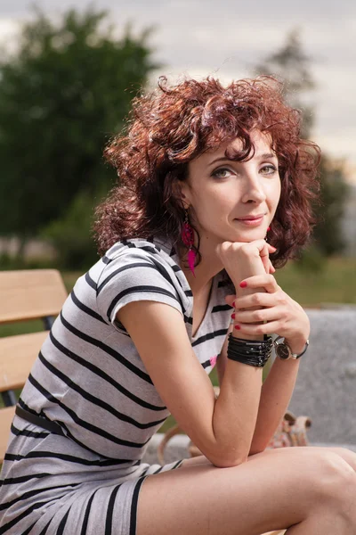 Ein schönes Mädchen sitzt auf einer Parkbank — Stockfoto