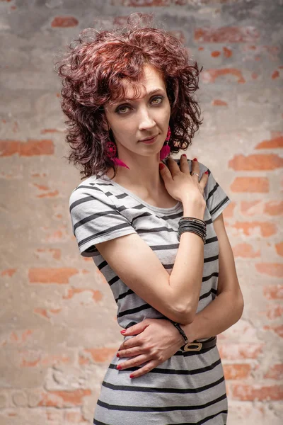 Schöne rote lockige Haare Frau gegen Ziegelmauer — Stockfoto