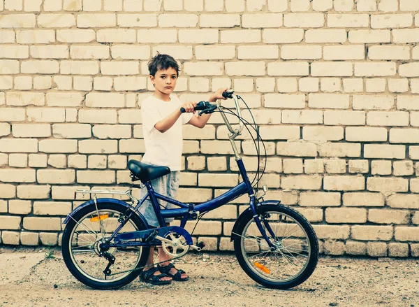 Мальчик и велосипед против кирпичной стены — стоковое фото