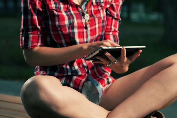 Vrouwen in het rode shirt met behulp van tablet pc buiten zitten in lotus asana — Stockfoto