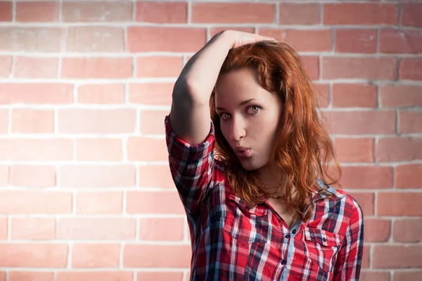 Ragazza dai capelli rossi posa contro muro di mattoni rossi — Foto Stock