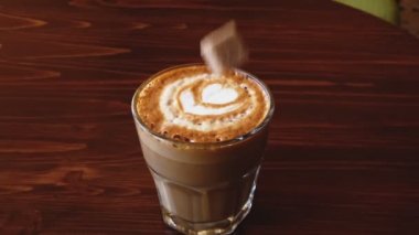 Şeker küpleri küçük bembeyaz kahve bardağına dökülüyor ve yavaşça masanın her tarafına su sıçrıyor.