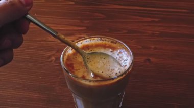 Bardakta düz beyaz kahve, ağır çekimde POV kaşığı sıvıdan alıyor ve kahveyi geri koyuyor.