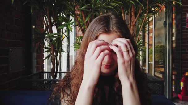 Pěkná dívka se opravuje její vlasy a pak se dívá pryč od kamery s plachým úsměvem — Stock video