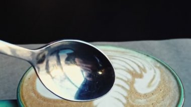 Bir kaşık kaşık kabı üstünde köpükle kahve bardağının içine giriyor.