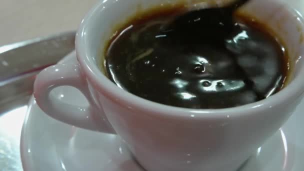 Stirring a cup of black espresso coffee with spoon on silver table — Stock Video