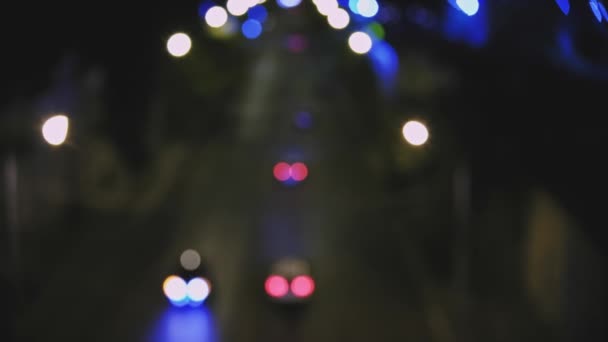 Coches y camiones en movimiento desenfocados. Las luces borrosas pasan por la calle de la ciudad por la noche desde arriba — Vídeo de stock