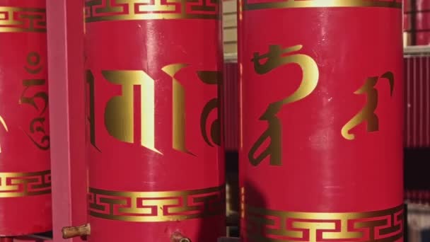 Beautiful Tibetan prayer wheels of red color. Tibetan buddhist praying wheels in Elista, Russia. Mantra Om Mani Padme Hum written in Sanskrit Tibetan Mongolian on the outside of the wheels — Stock Video