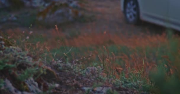 Kippaufnahme des an der wilden Küste geparkten Autos und des Sonnenuntergangs auf verschwommenem Hintergrund. — Stockvideo