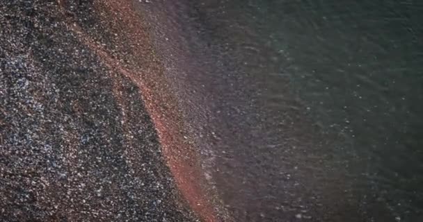 Vista aérea en olas verdes del mar que corren sobre la arena en la luz oscura del atardecer. — Vídeo de stock