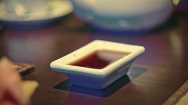 Suşi soslu soya kabına sarılmış bir kadın onu yemek çubuklarıyla tutarken....