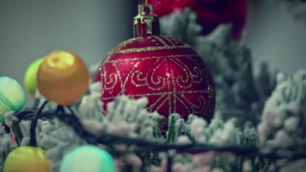 Defokussierte Weihnachtslichter aus Weihnachtsgirlanden, die um eine verzierte rote Kugel leuchten. Weihnachtliches Video — Stockvideo