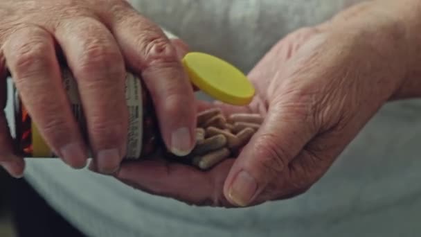 Mulher sênior derramando pílulas de ervas para fora da garrafa pílula. Um punhado de comprimidos de cânhamo — Vídeo de Stock