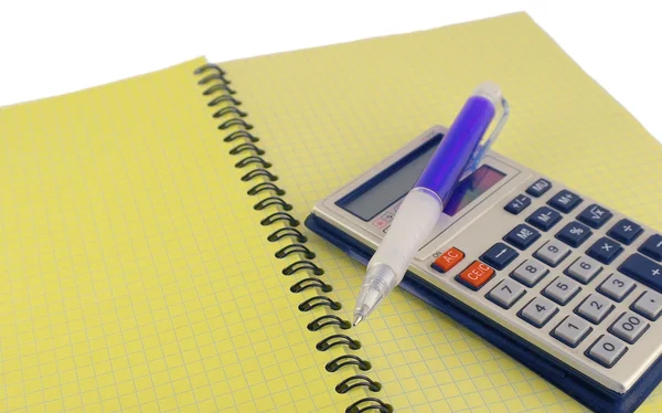 Calculator and pen on the yellow writing-book — Stock Photo, Image