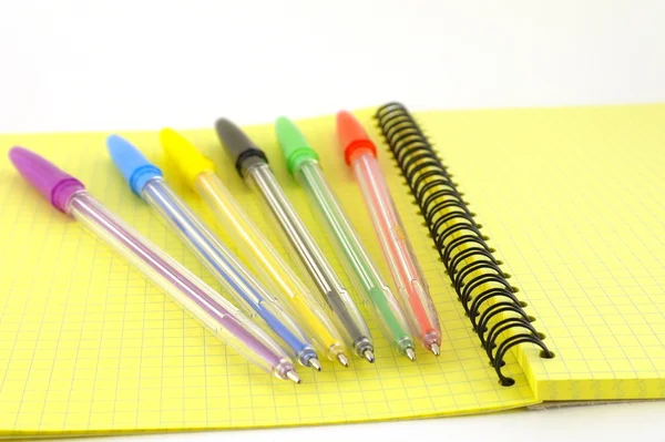 Color pens on the yellow writing-book — Stock Photo, Image