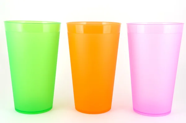 Green, orange and pink cups over white — Stock Photo, Image