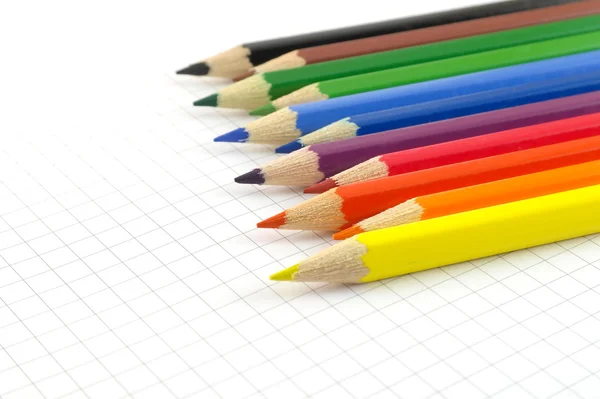 Color pencils on the checked paper of notepad — Stock Photo, Image