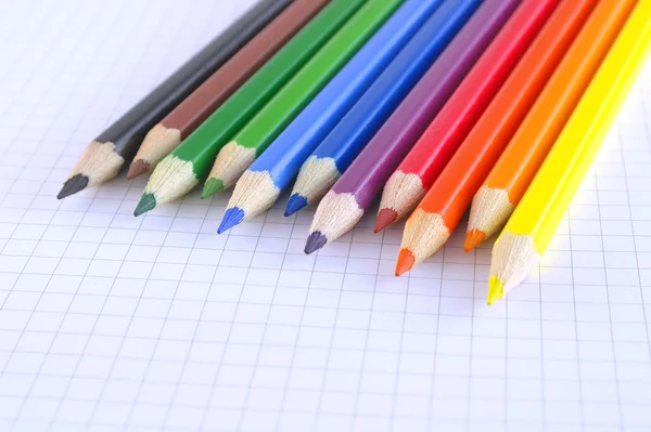 Crayons de couleur sur le papier à carreaux du bloc-notes — Photo