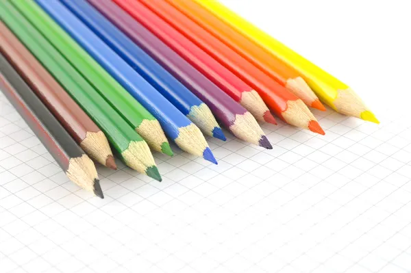 Lápices de color en el papel comprobado del bloc de notas — Foto de Stock