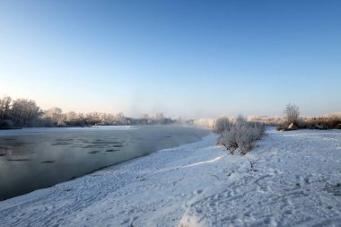 Nehir ve ağaçlarla kaplı kış manzarası