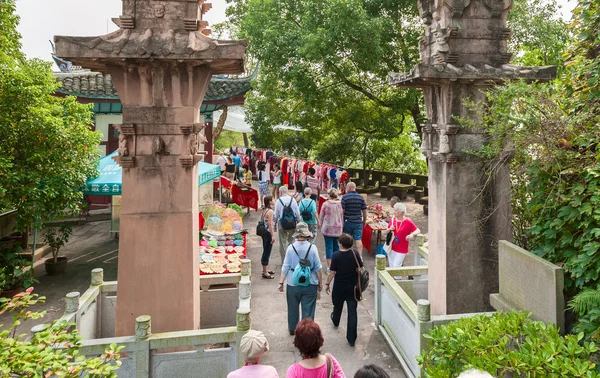 Tourists walk on the sidewalk between the stone columns — Stock Photo, Image