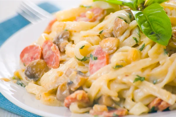 Pasta with mushrooms, smoked sausage and cream sauce with basil — Stock Photo, Image