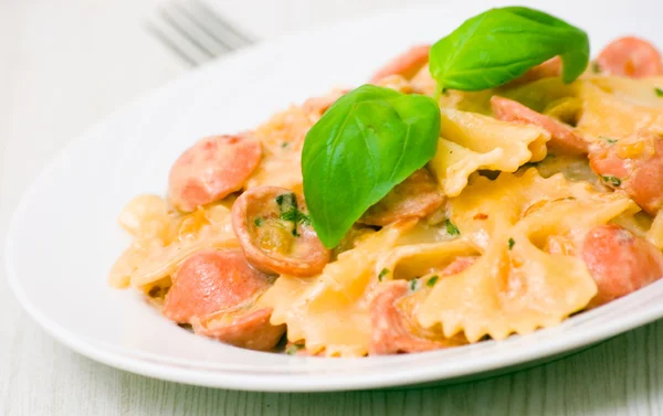 Farfalle pasta with sausage and cream sauce with basil — Stock Photo, Image