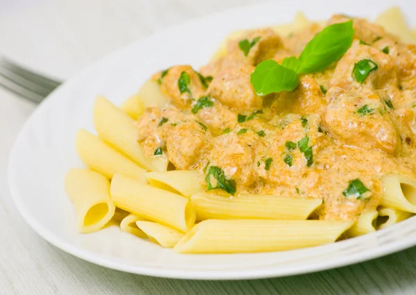 Penne pasta with chicken meat, cream sauce and basil — Stock Photo, Image