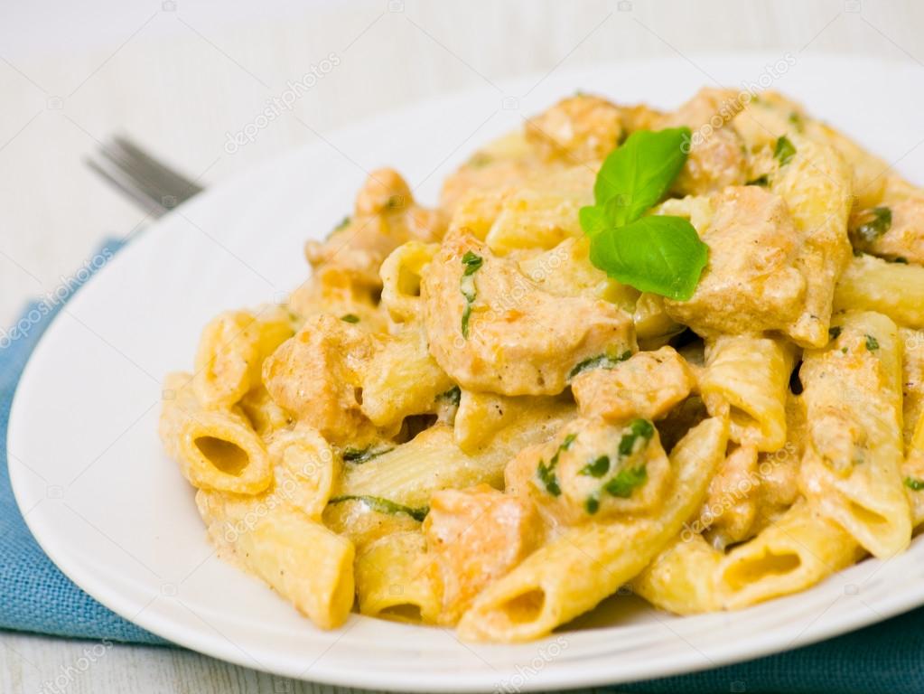 Penne pasta with chicken meat, cream sauce and basil