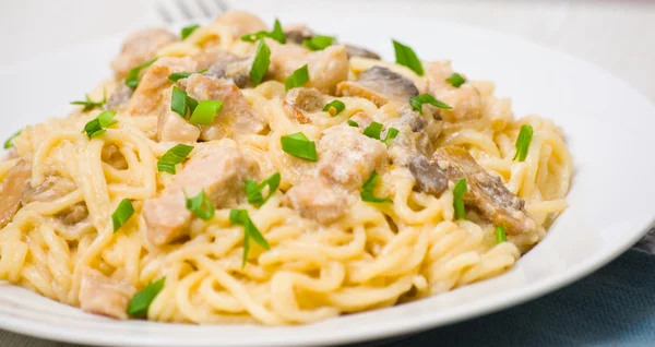 Spaghetti with meat and mushrooms in a creamy sauce — Stock Photo, Image