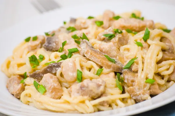 Spaghetti with meat and mushrooms in a creamy sauce — Stock Photo, Image