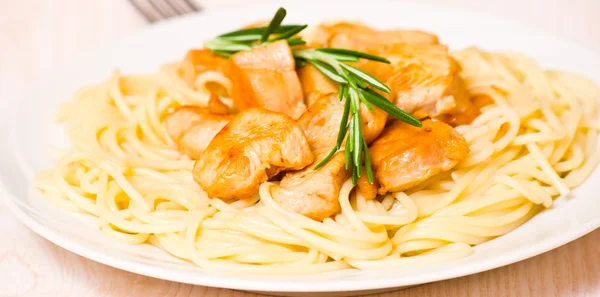 Sliced fried chicken fillet with garlic and rosemary. garnish spaghetti — Stock Photo, Image