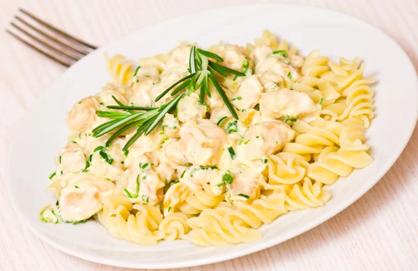 Filet de poulet frit tranché avec ail et romarin dans une sauce crémeuse. aux pâtes fusilli — Photo