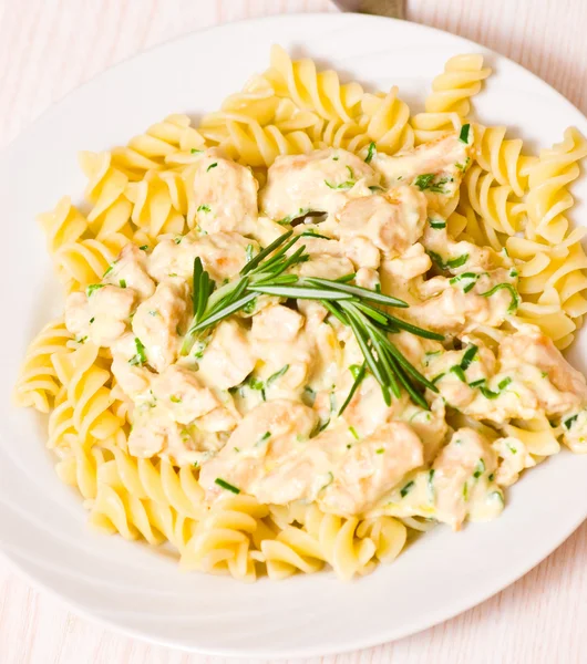 Sliced fried chicken fillet with garlic and rosemary in a creamy sauce. with fusilli pasta — Stock Photo, Image