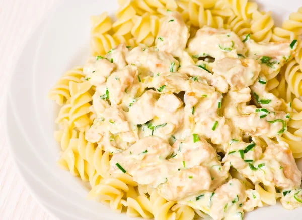 Sliced fried chicken fillet with garlic and rosemary in a creamy sauce. with fusilli pasta — Stock Photo, Image