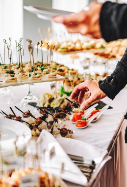 Erkek eli bir aperatif alır ve tabağa koyar. Bir restoranda açık büfe.