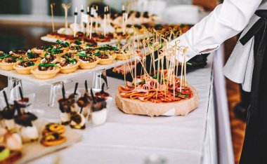 Bir garsonun kadın eli bir restoranda açık büfe masası için yemek hazırlar.