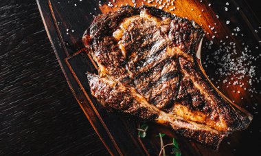 Tahtada kemikli ızgara Ribeye bifteği, arka planda kaliteli kovboy bifteği.