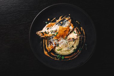 Koyu arkaplanda patates püresi ve kereviz olan uskumru filetosu.