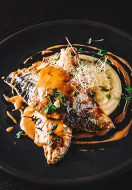 Koyu arkaplanda patates püresi ve kereviz olan uskumru filetosu.